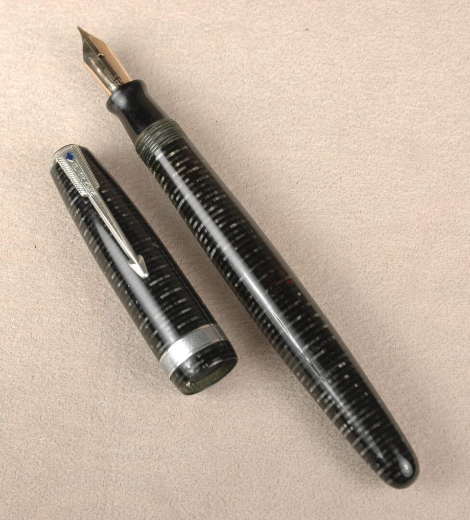 Vintage fountain pen with cap on beige surface, after restoration