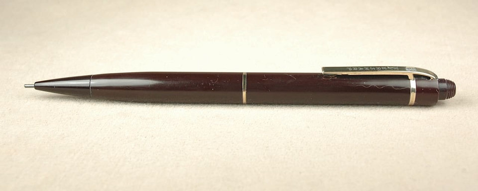 Brown mechanical pencil on beige background.