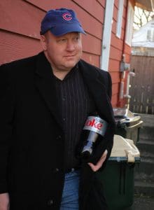 Man in coat holding Diet Coke bottle.