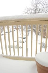 Snow-covered balcony and parked cars outside.