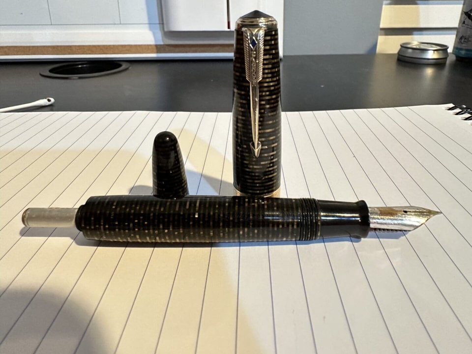 Vintage fountain pen disassembled on lined paper.