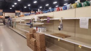Empty supermarket shelves with few products.