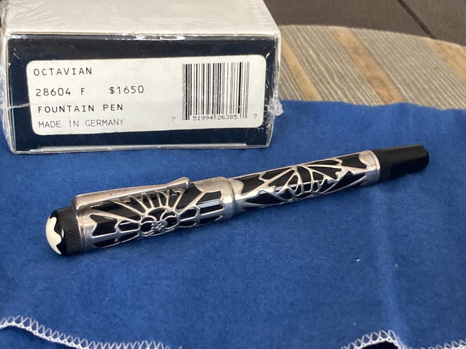 Intricately designed black and silver pen with geometric patterns on a blue cloth.
